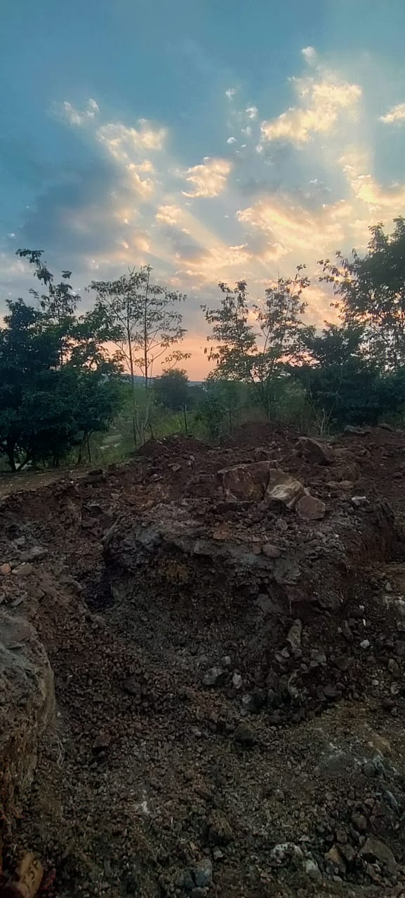 Broader excavation pits dug through hard, rocky ground