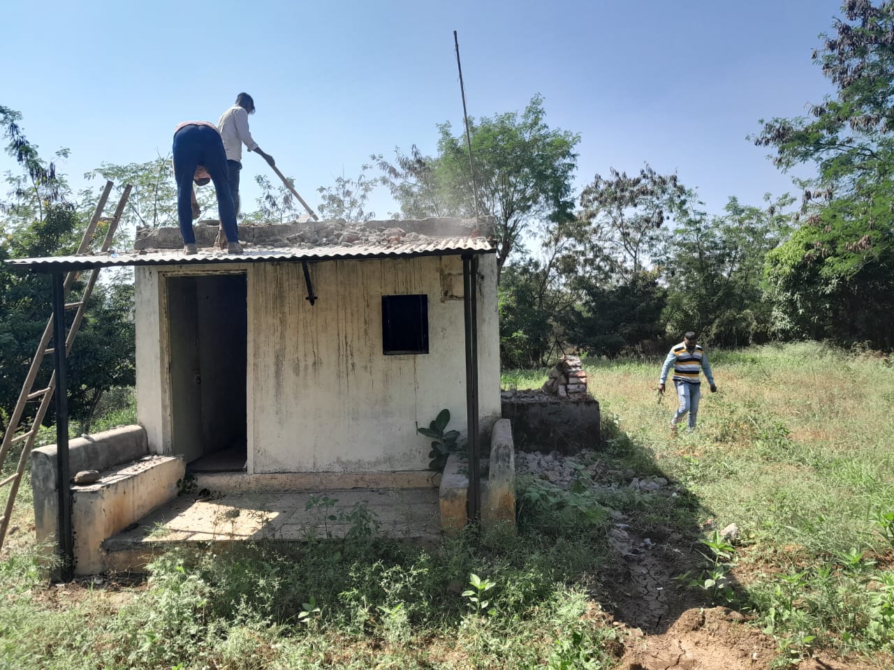 Workers dismantling the old cement storage room by hand